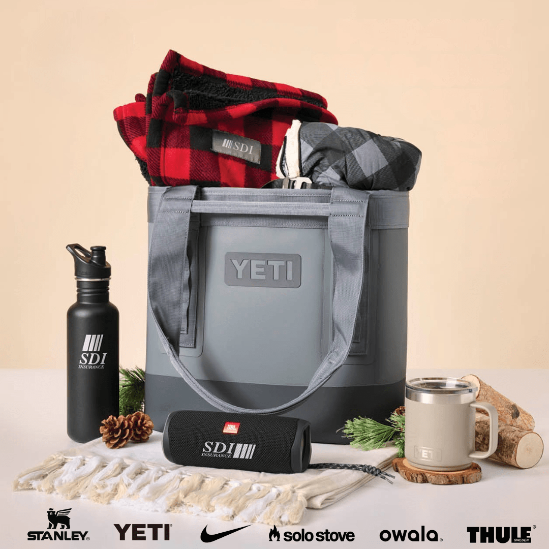 Yeti cooler bag with plaid blanket, SDI water bottle, and other items on a beige background